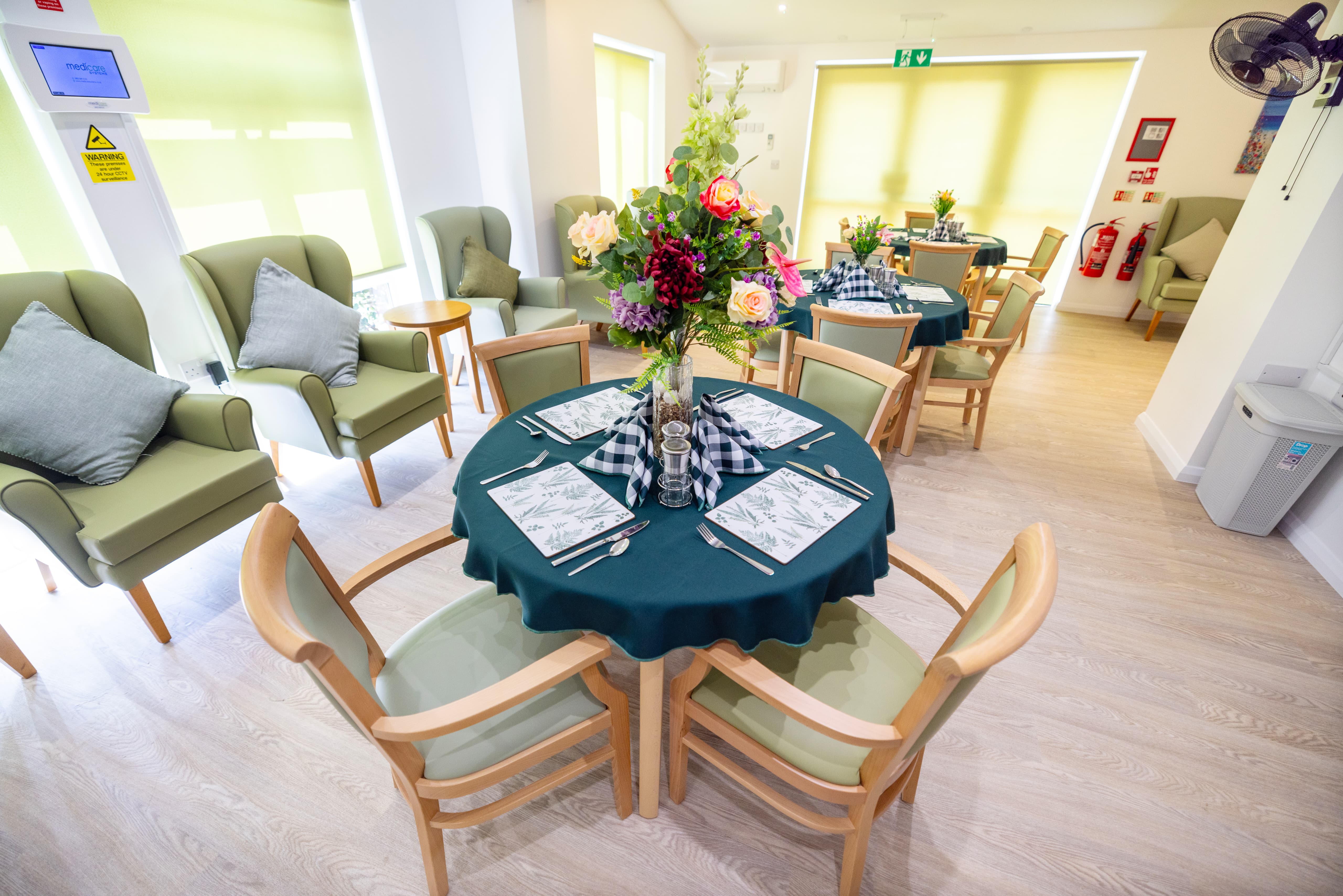 Dining and lounge area with sage green chairs and elegant table settings