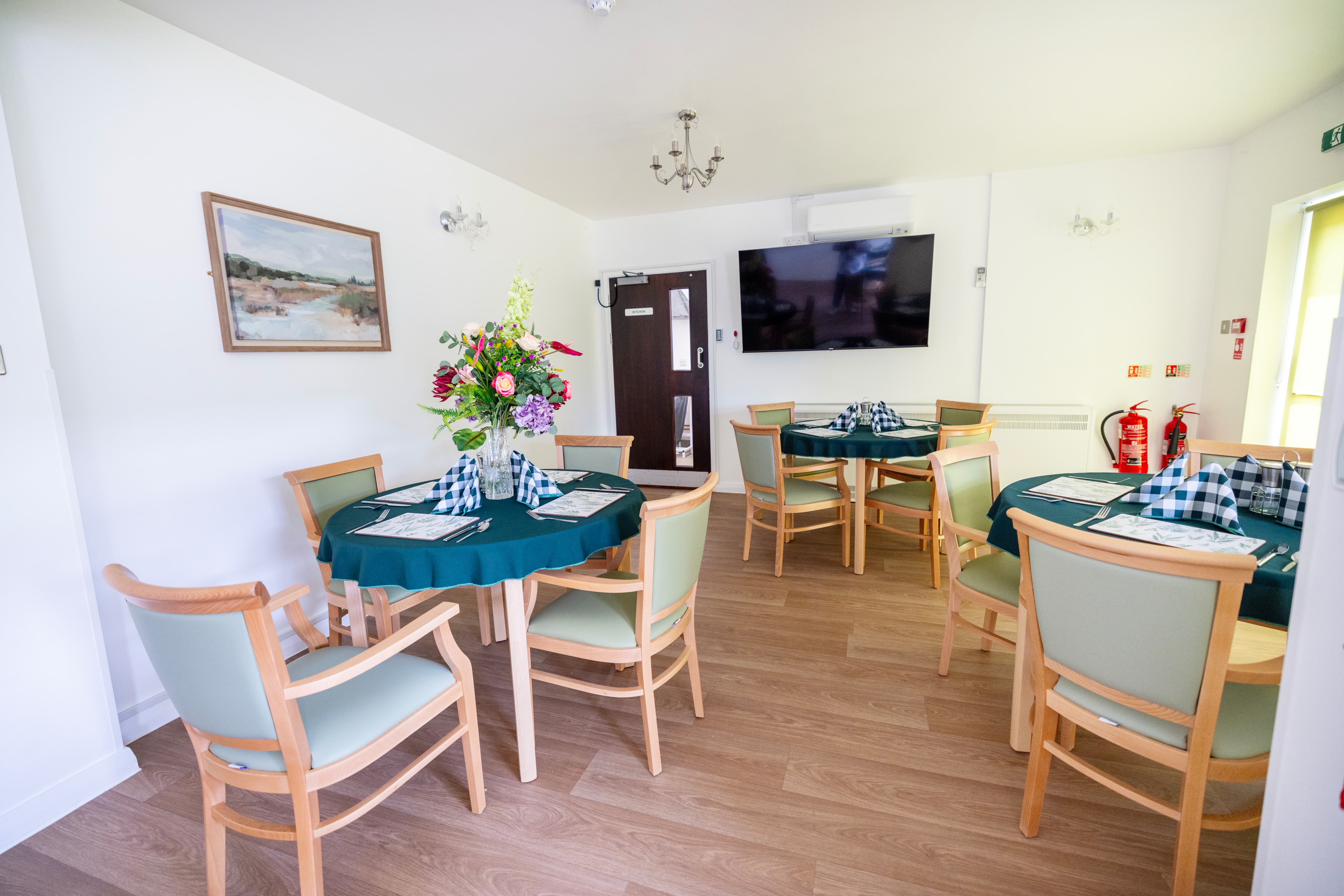 Elegant dining room with sage green chairs and teal tablecloths