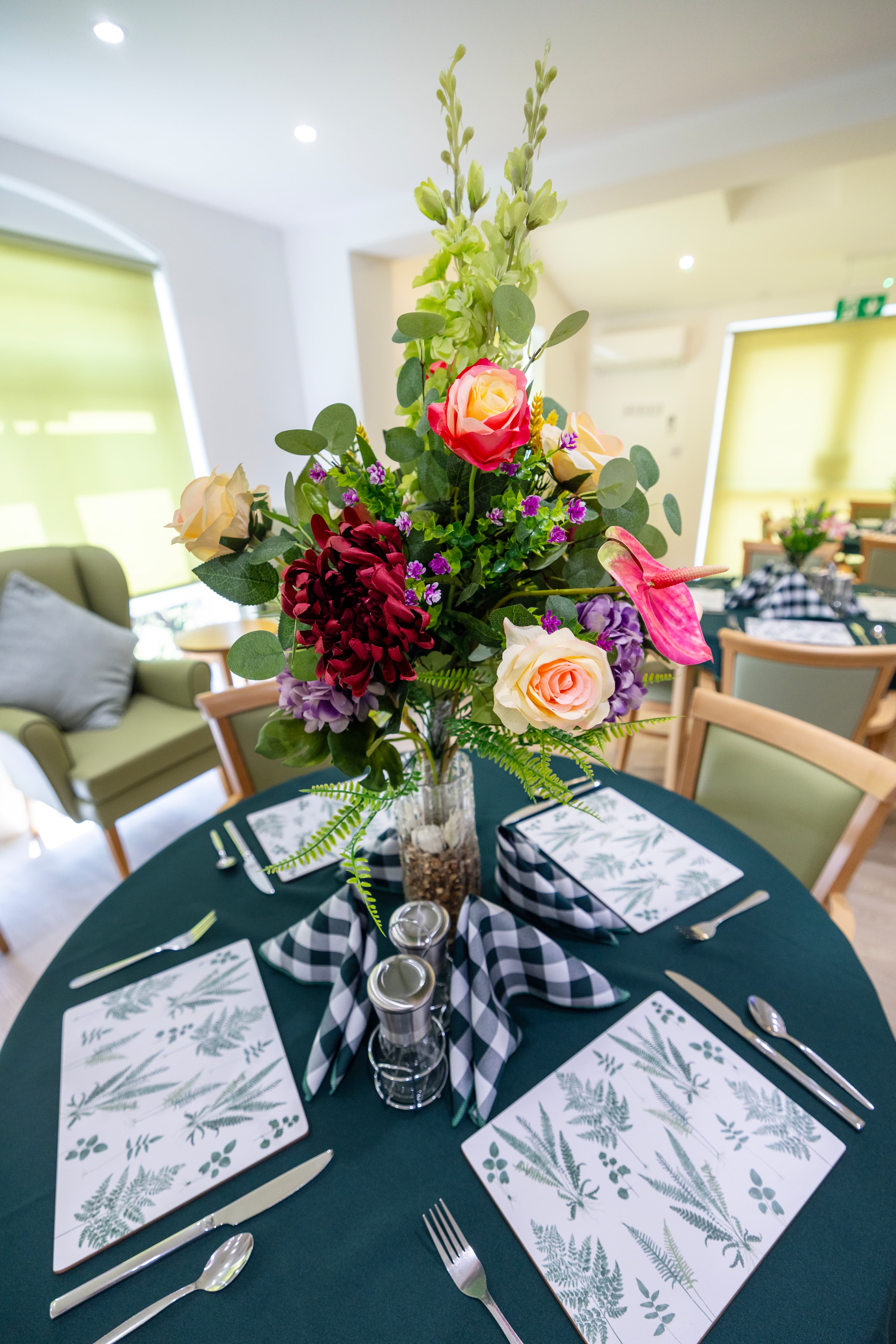 Beautiful floral centerpiece with roses and ferns on dining table