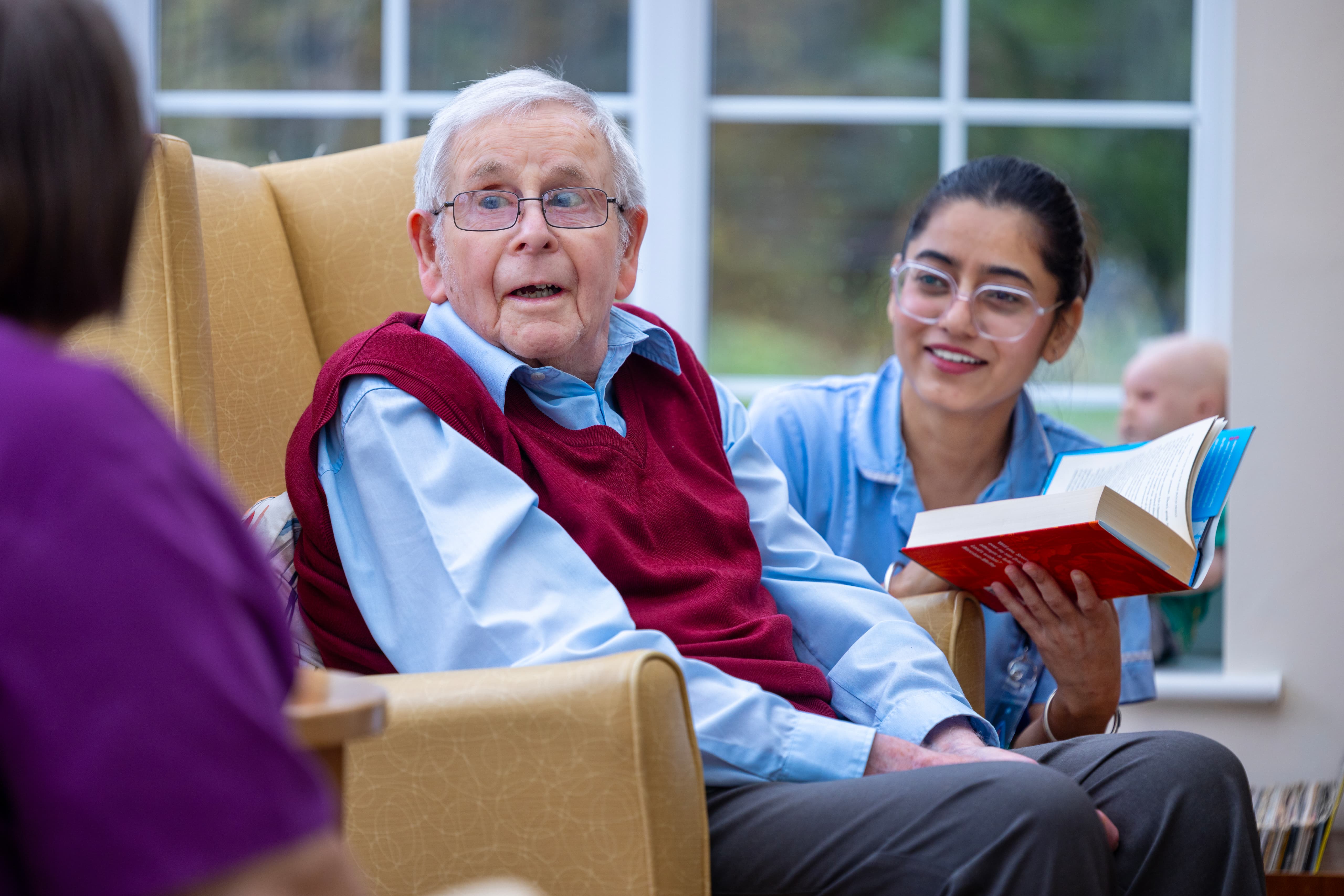 Care worker reading to elderly resident