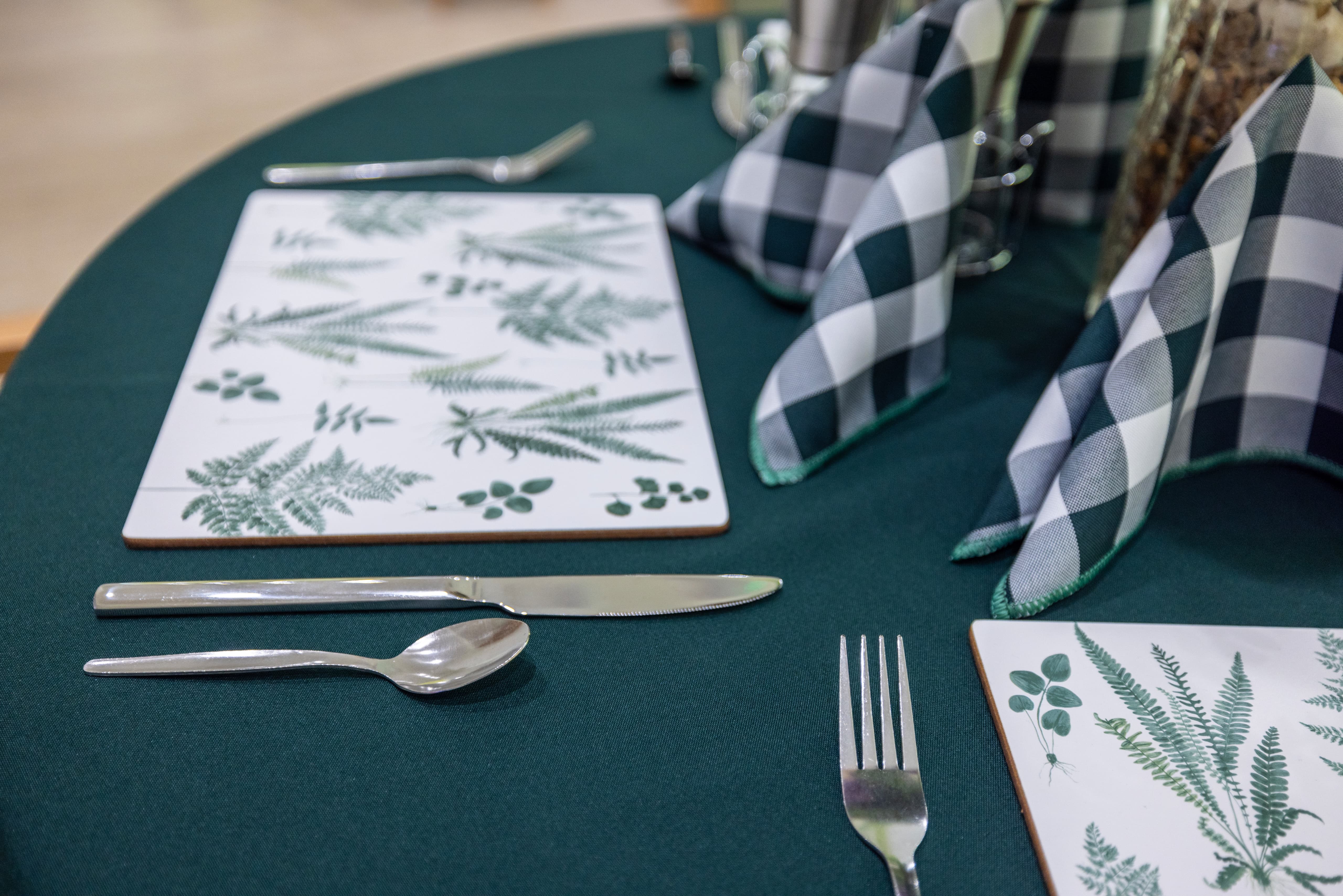 Close-up of elegant table setting with botanical placemats and teal tablecloth